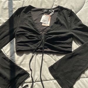 Black cropped, long sleeve shirt with gold detailing.